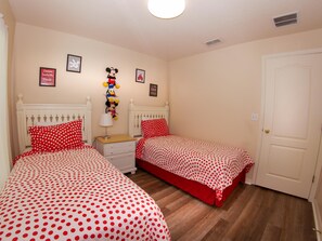 A bedroom with two beds, each with red polka dot bedding, a nightstand with a lamp, and wall decorations including framed pictures and a Mickey Mouse figure. - Great Community, amazing private pool, near Disney! (Davenport)