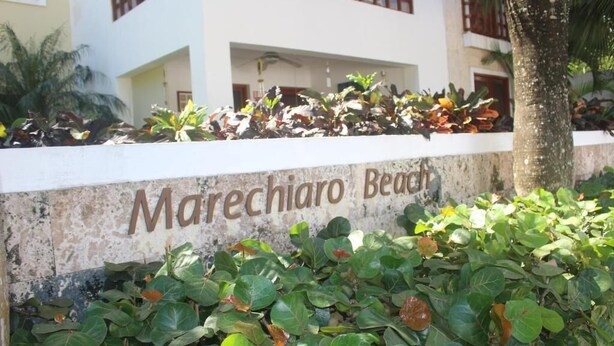 Et skilt med teksten 'Marechiaro Beach', omgivet af frodig vegetation.