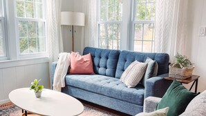A living room with a blue sofa, a round coffee table, and a patterned rug.