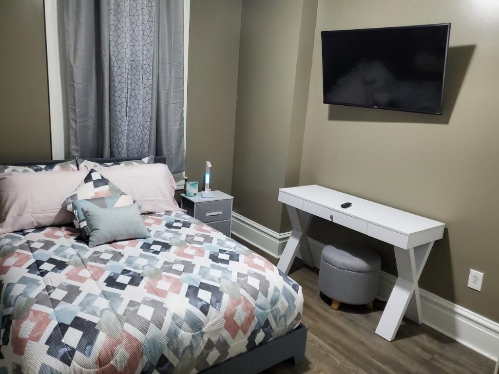 Une chambre à coucher comprenant un lit, une table de chevet, une télévision, un bureau et une chaise.