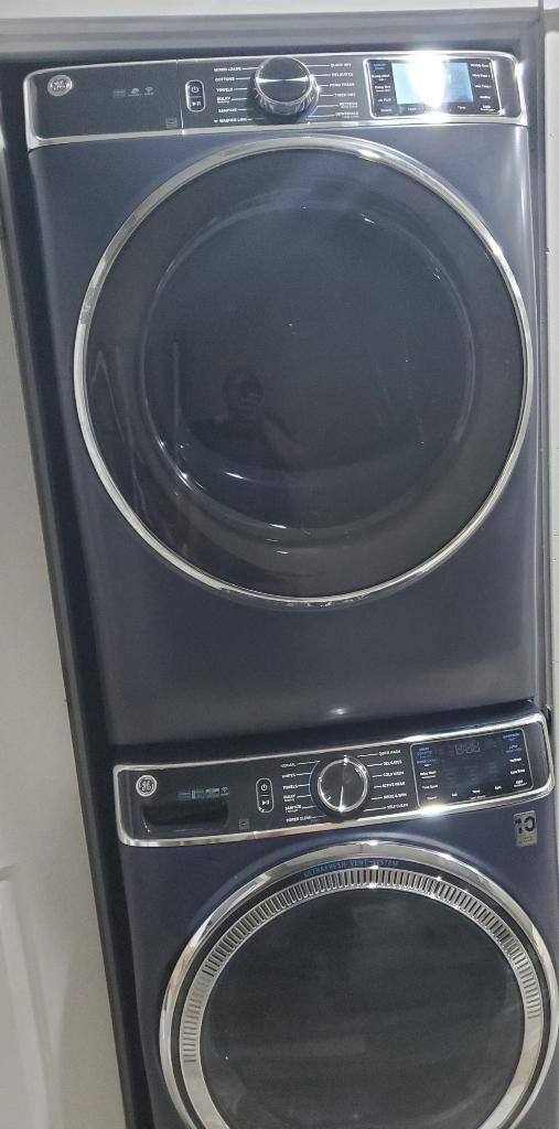 A front view of a stacked washer and dryer unit with control panels and a transparent door.