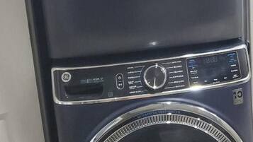 A front view of a stacked washer and dryer unit with control panels and a transparent door.