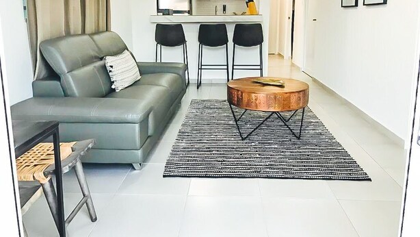 Una sala de estar moderna con un sofá gris, una mesa de centro redonda y un tapete a rayas blanco y negro.