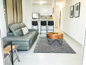A modern living room with a grey sofa, a round coffee table, and a black and white patterned rug.