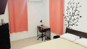 Un dormitorio con una cama, un escritorio y dos cortinas rosadas.