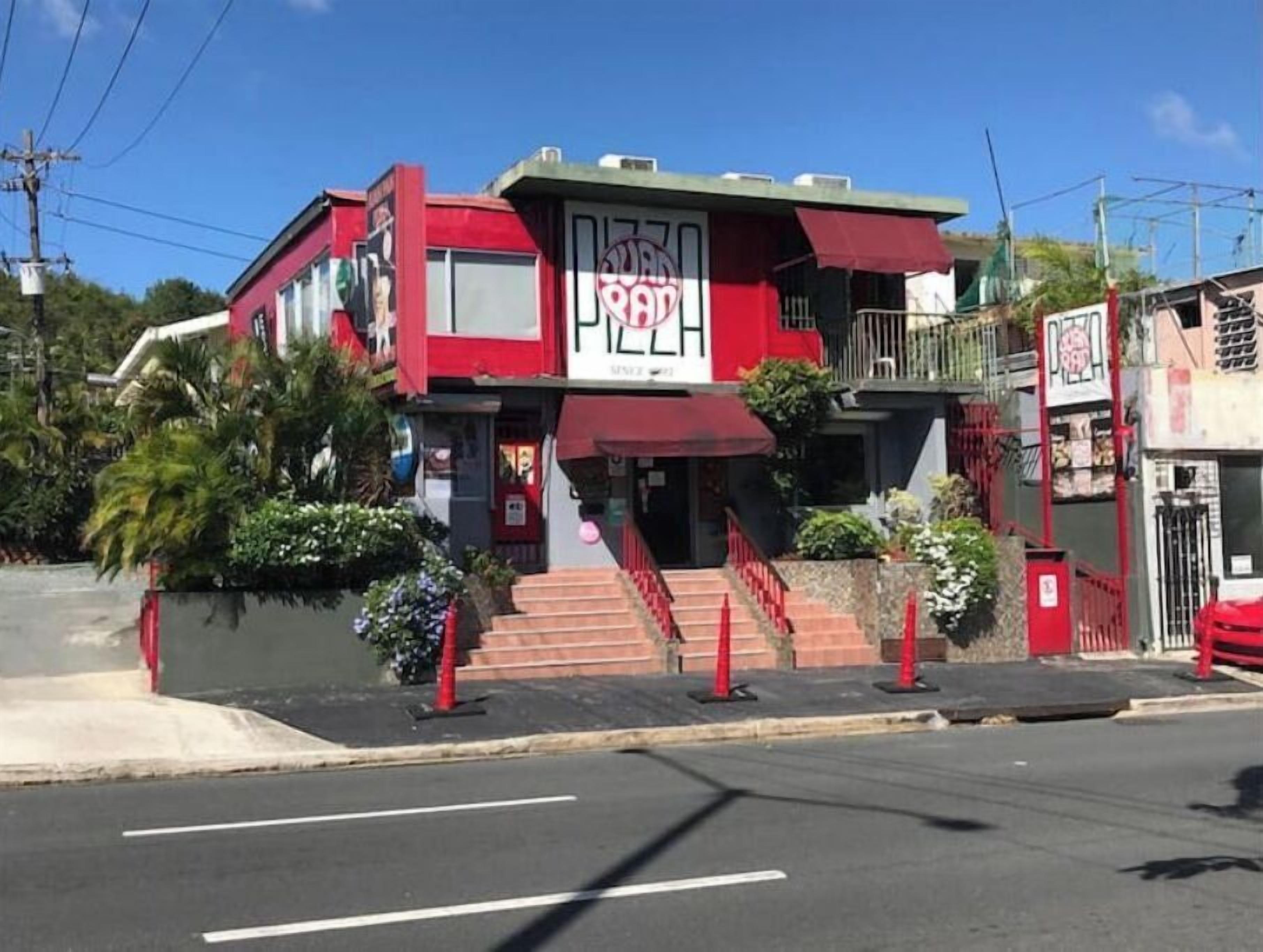 A building with a red and white facade, a visible entrance, and a staircase leading to the entrance.