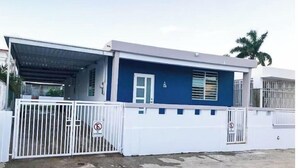 Un edificio de dos plantas con fachada azul, portones blancos y un acceso cubierto.