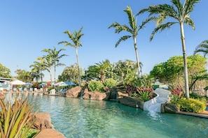 A pool area with clear water, palm trees, and lounge chairs.