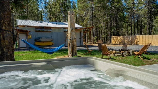 Een hottub met een houten terras, een hangmat en zitplaatsen buiten.