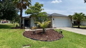 A residential house with a well-maintained lawn, palm trees, and a garage. - Palm Tree Fairways (Haines City)