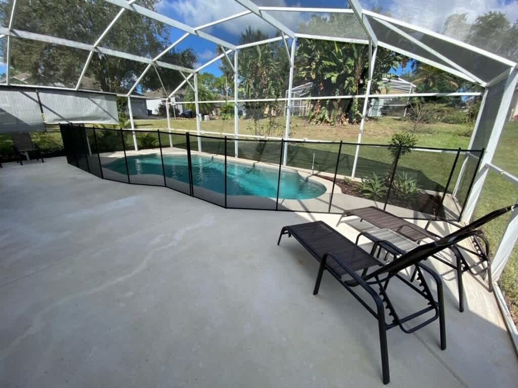 Ein überdachter Außenbereich mit Pool, Liegestuhl und Tisch.