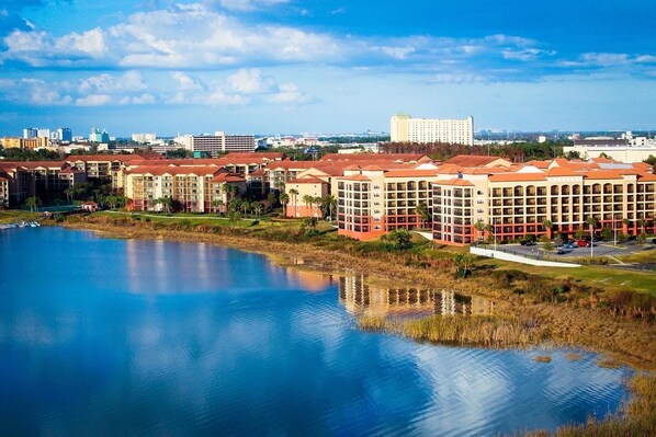 A hotel complex with multiple buildings, a large body of water, and a distant city skyline.