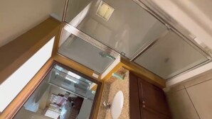 Een badkamer met een douchecabine van glas, een wastafel en houten kastjes.