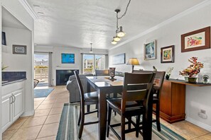 A spacious dining area with a wooden table and chairs, a chandelier, and artwork on the walls.