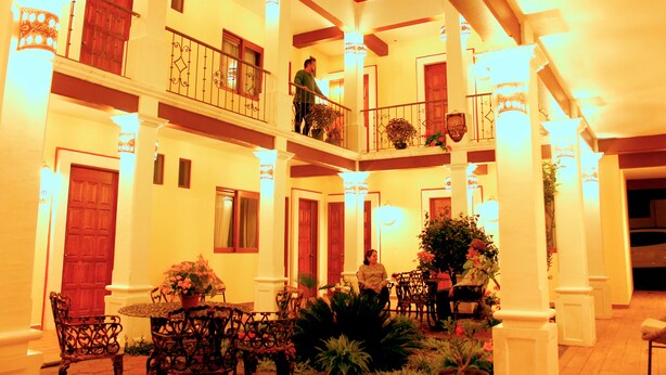 Hotel de varios niveles con un patio central, que cuenta con balcones, un comedor y una escalera.