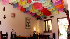 Un comedor con muebles de madera, un techo decorado con adornos de papel de colores y una puerta que da al exterior.