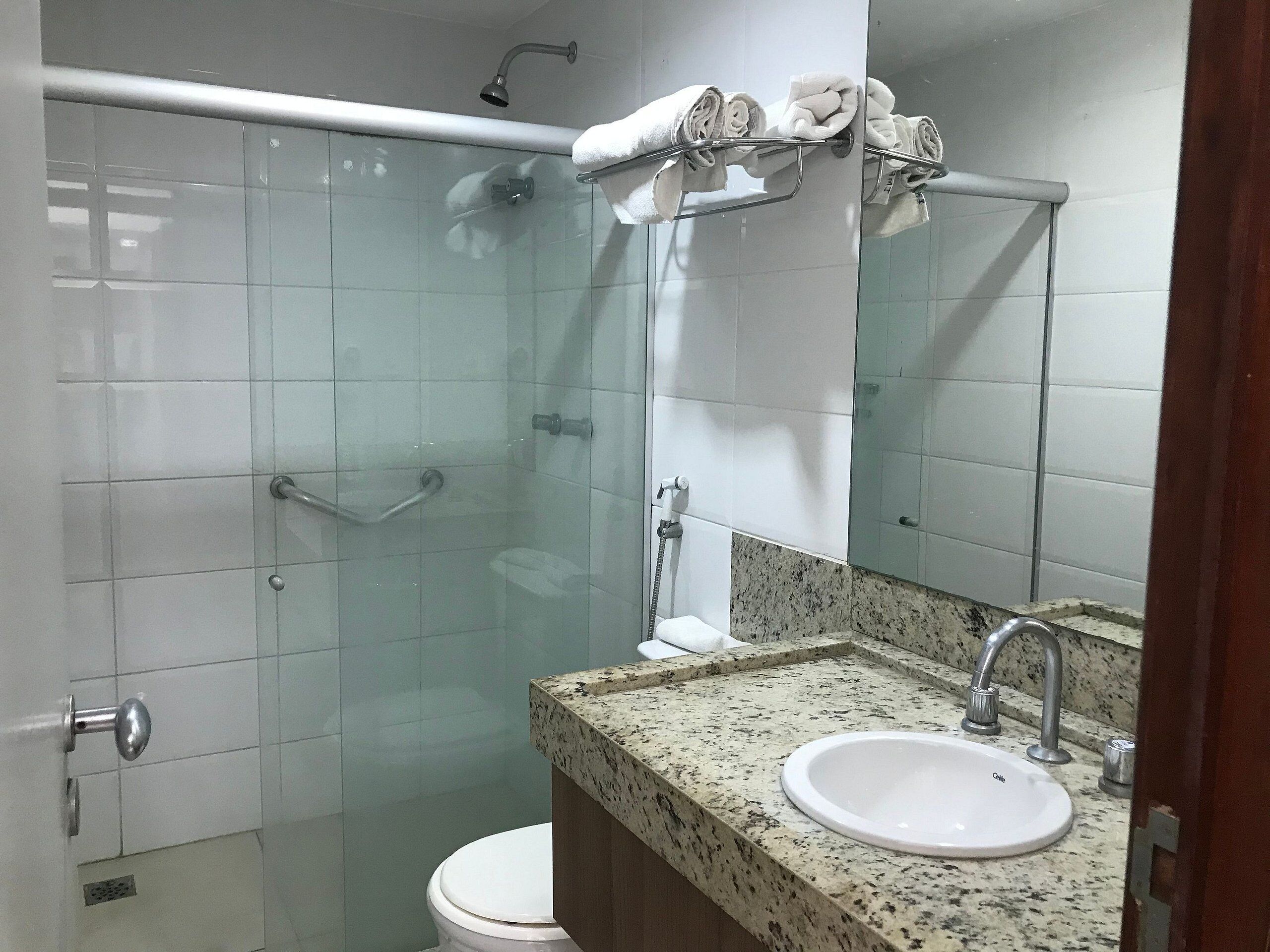 Ein Badezimmer mit Duschkabine aus Glas, einem weißen Waschbecken und einem Spiegel darüber.