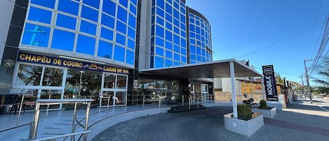 A modern building with a glass facade, a covered entrance, and a sign for 'CHAPÉU DE COURO'.