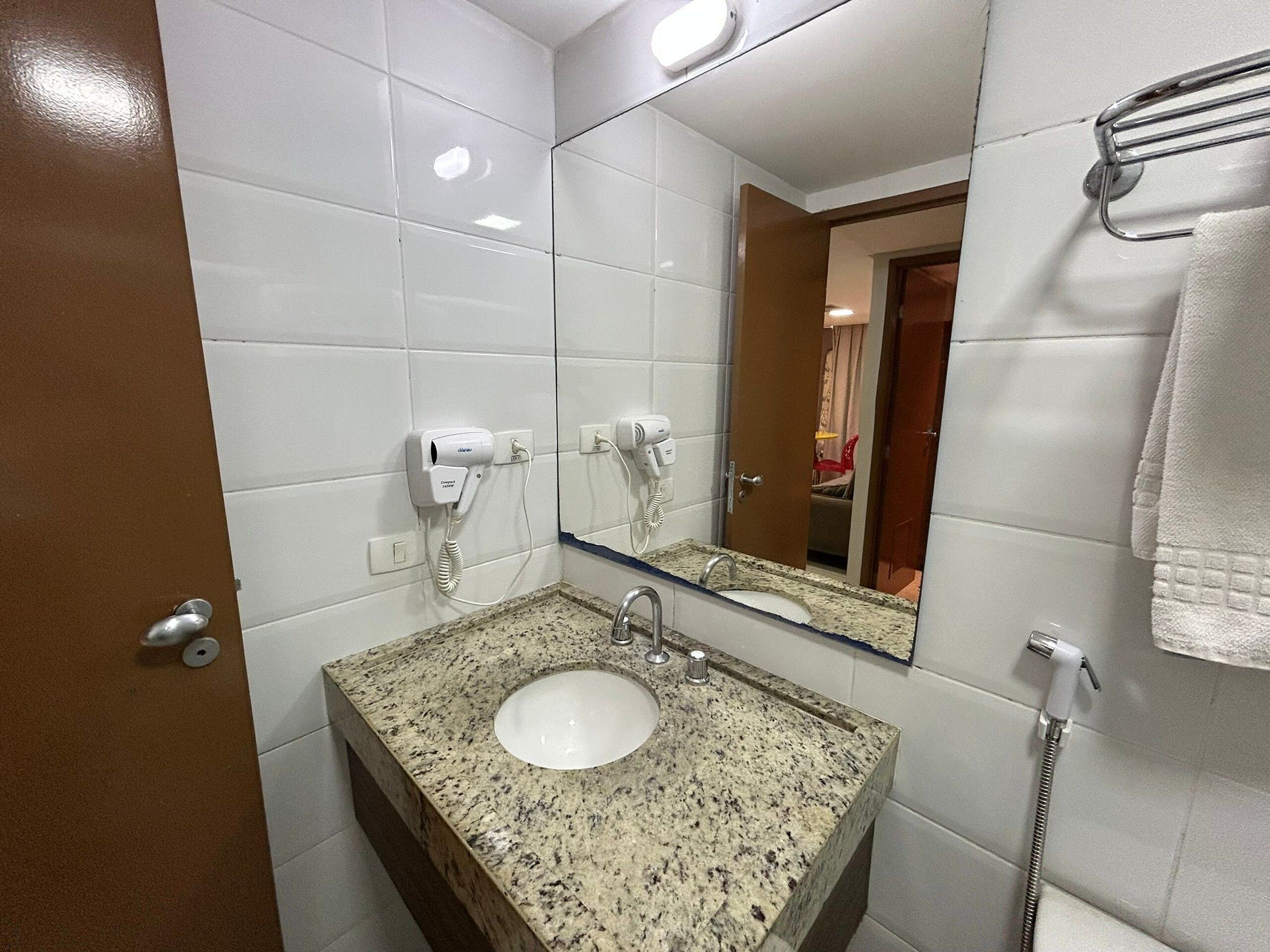 A bathroom with a sink, mirror, towel rack, and hairdryer.