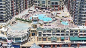 A high-rise hotel with multiple balconies, a central courtyard with pools, and a prominent tower structure. - Bright Corner Unit with Stunning Gulf Views & Sunsets (Destin)