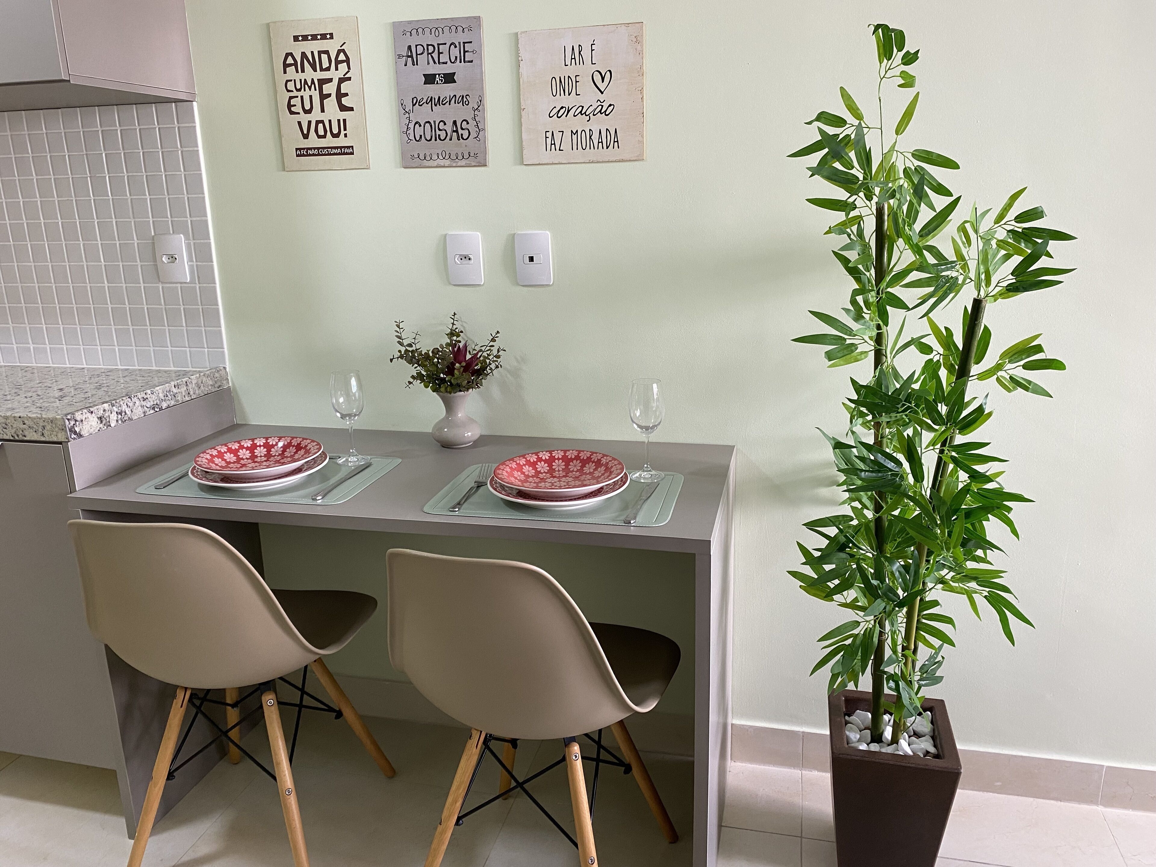 A dining area with two chairs, a table, a vase with flowers, and a potted plant.