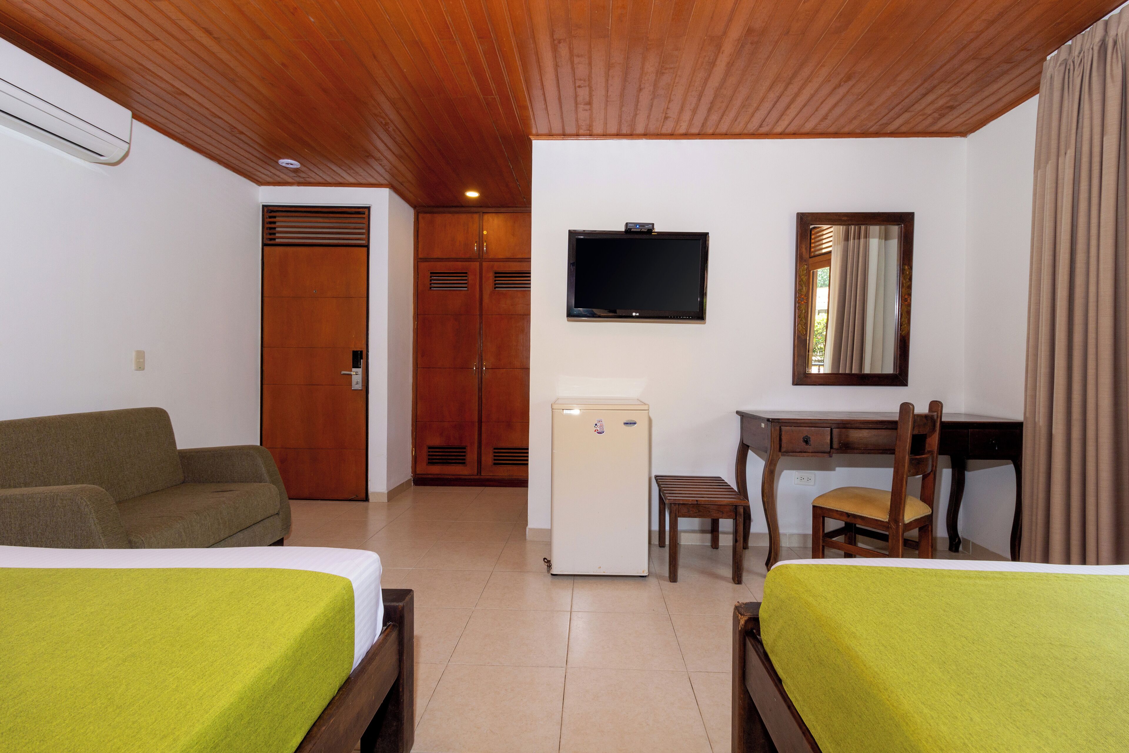 Une chambre d’hôtel avec deux lits, un bureau, une chaise, une télévision et une armoire.