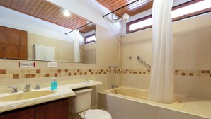 Een badkamer met een bad, toilet, wastafel en spiegel.