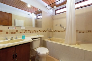 Een badkamer met een bad, toilet, wastafel en spiegel.
