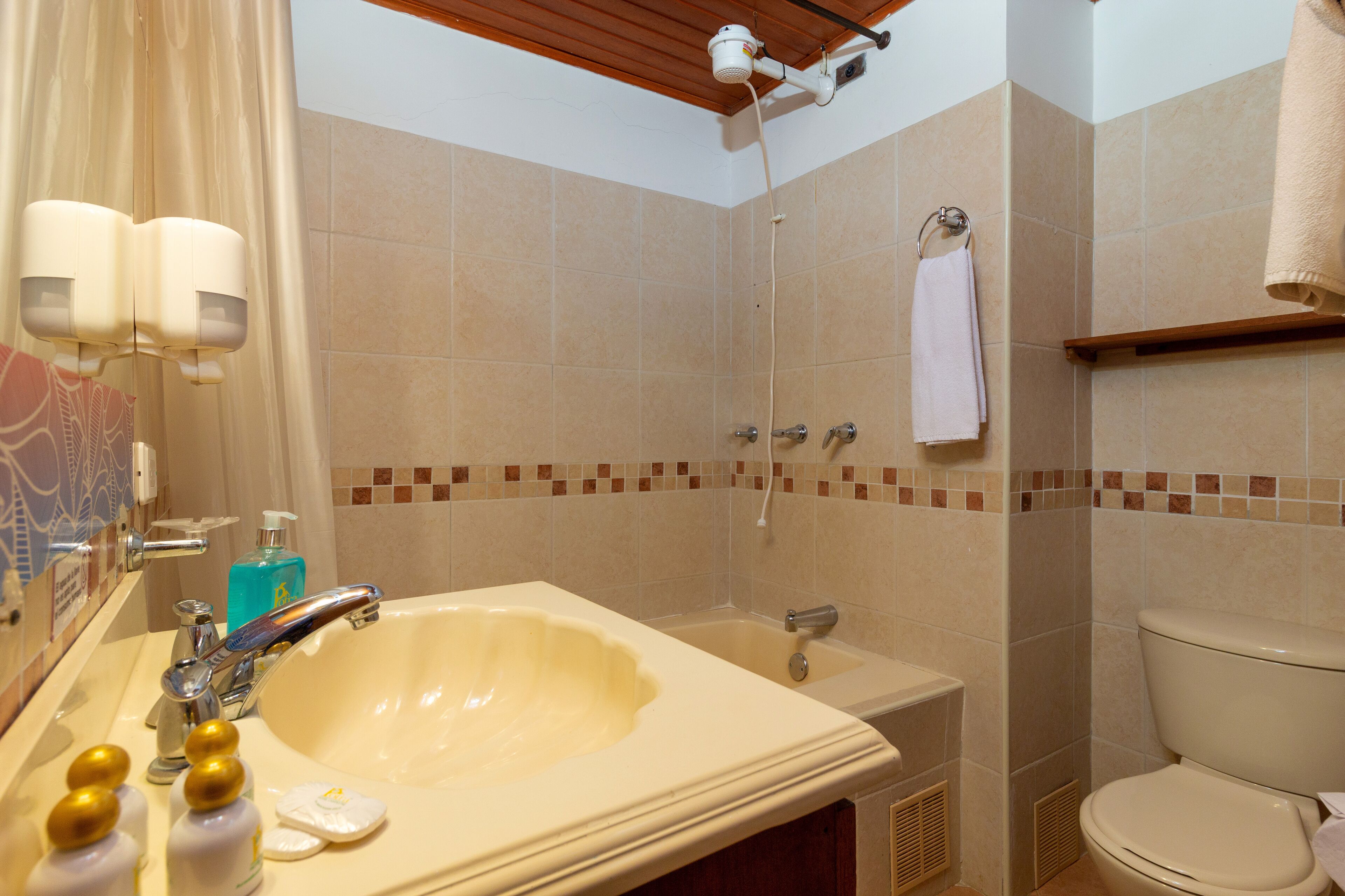 A bathroom with a large sink, a shower, and a toilet.