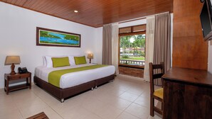 A hotel room with a bed, a desk, a chair, a TV, a window with curtains, and a painting on the wall. - Hotel Campestre La Potra (Villavicencio)