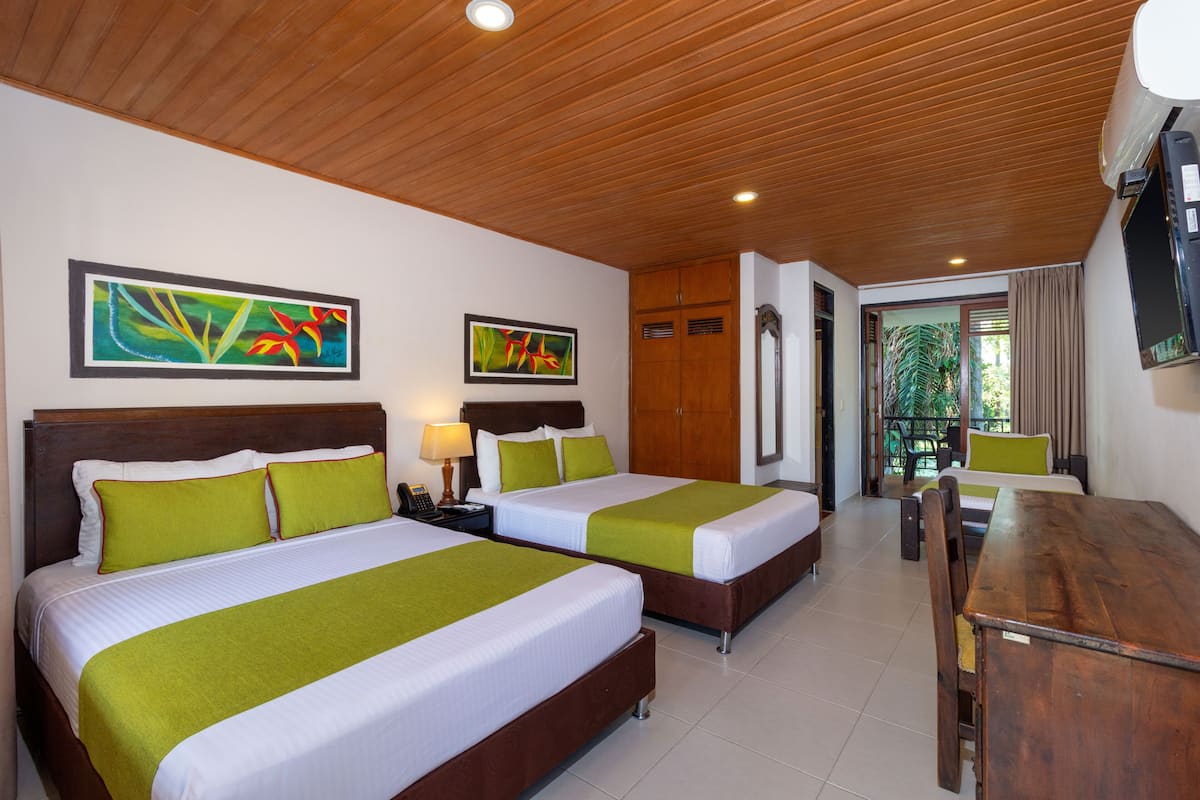 A hotel room with two beds, a wooden ceiling, and artwork on the walls.
