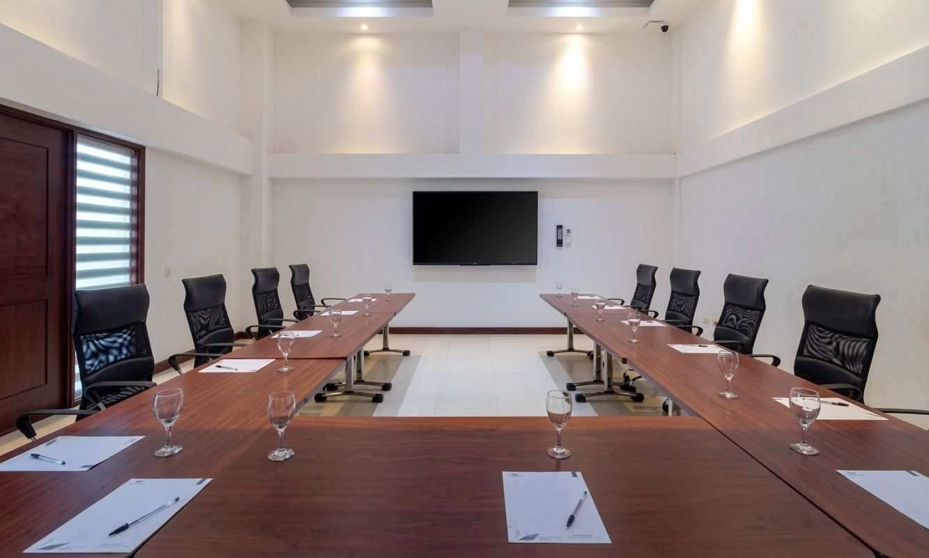 Un salón de conferencias con una larga mesa, sillas y una televisión de pantalla plana.