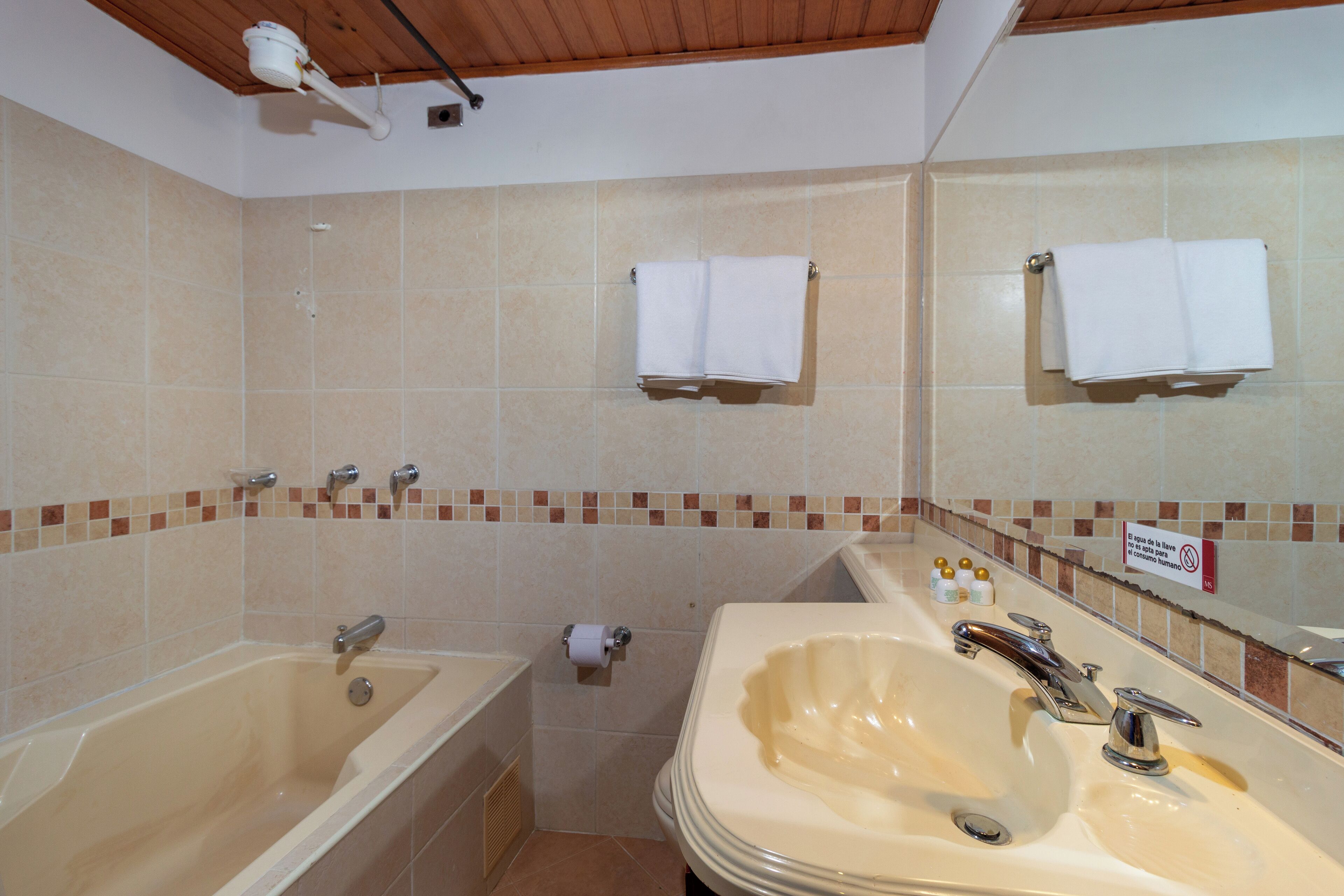 Un baño con bañera, lavamanos y dos toalleros.