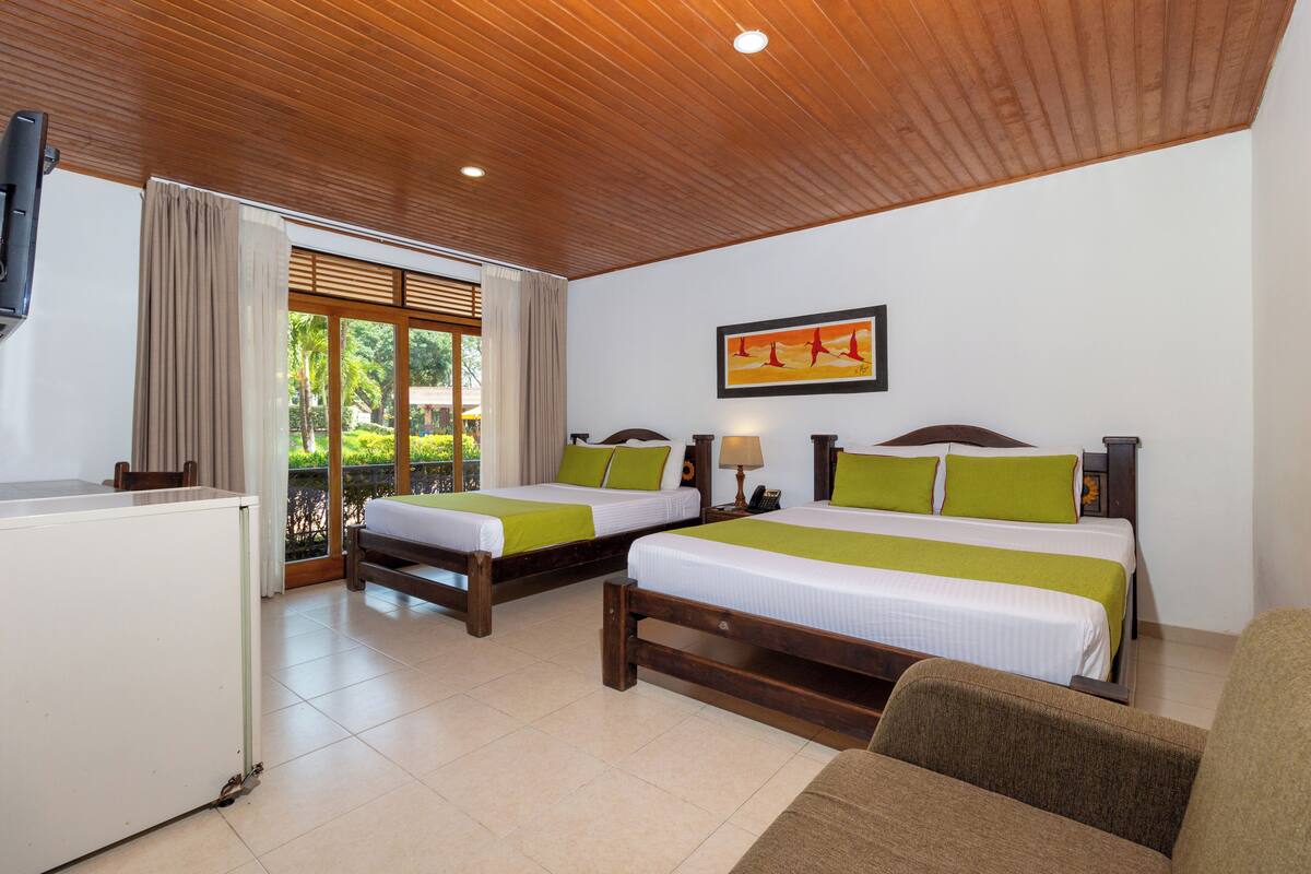 A hotel room with two beds, a desk, and a TV.