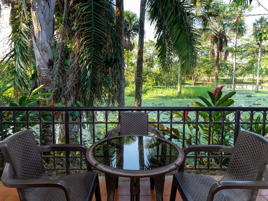 A round table with two chairs in a tropical garden setting.