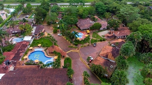 An aerial view of a resort with multiple buildings, a swimming pool, and lush greenery. - Hotel Campestre La Potra (Villavicencio)