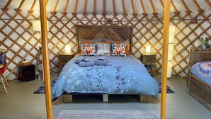 Una cama acogedora con una colcha estampada, cabecera de madera y dos lámparas de noche.