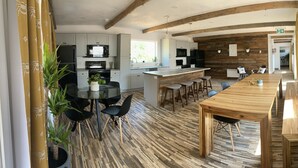Una cocina moderna con armarios blancos, una isla central con taburetes y una mesa de comedor de madera.