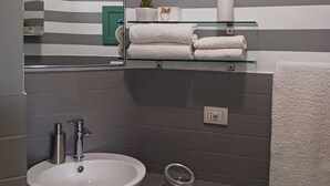 A modern bathroom with a white sink, a mirror, and striped walls.