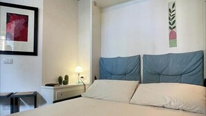 A bedroom with a bed, a bedside table, a lamp, and a framed picture on the wall.