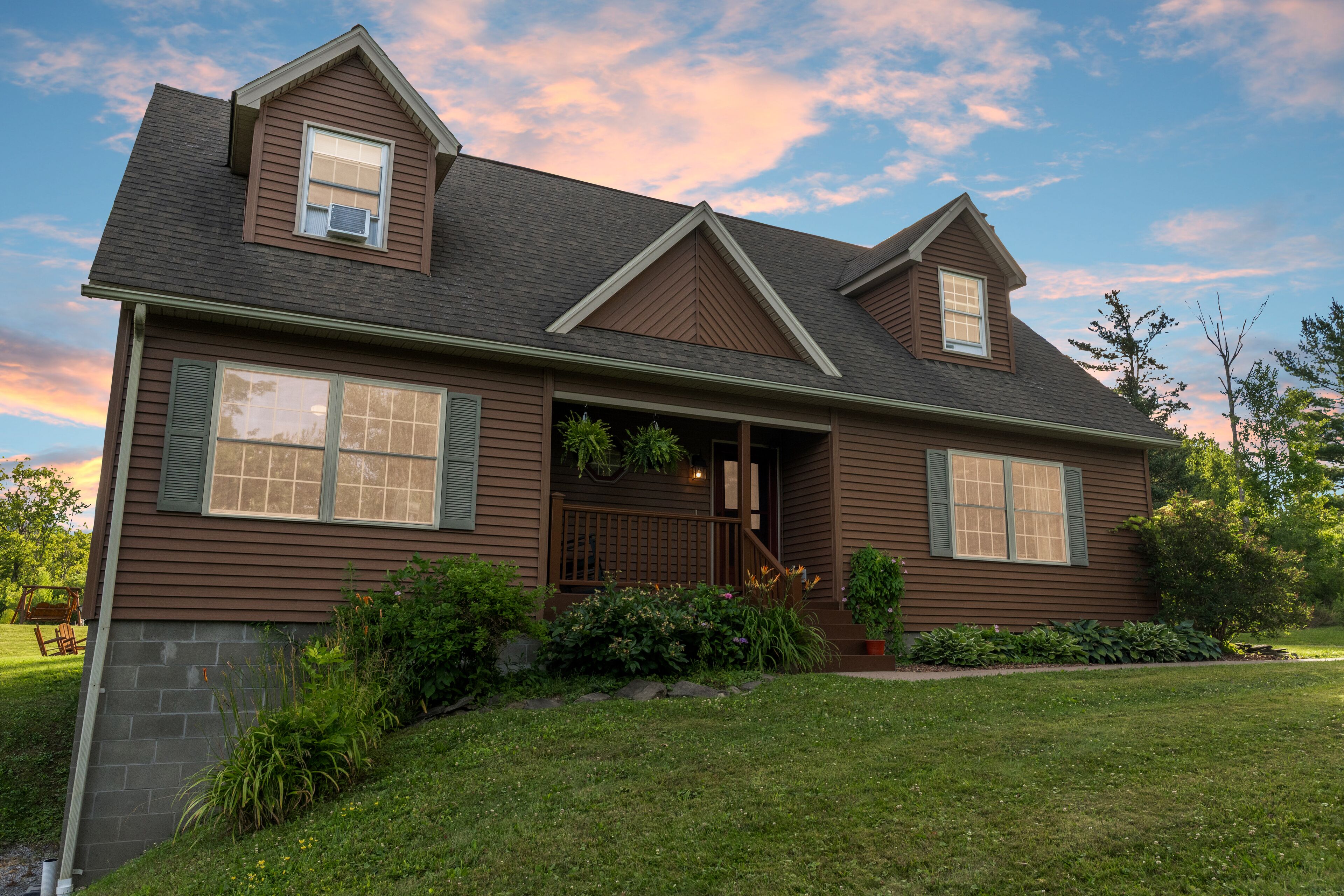 A two-story house with a front porch, a small garden, and a clear sky.