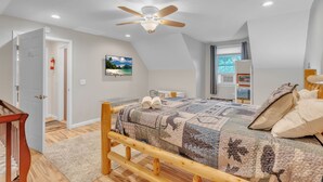 A bedroom with a wooden bed, a ceiling fan, and a view of the outdoors through a window.