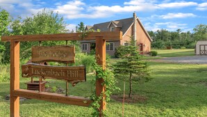 A wooden sign with "The Lodge at Luckenbach Hill" written on it, a house in the background, and a well-maintained lawn.