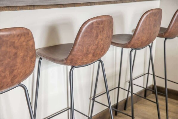 A row of four bar stools with metal legs and brown seats.