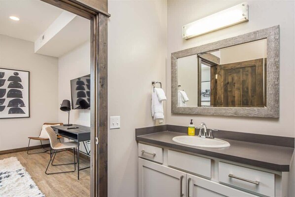 A bathroom with a large mirror, a sink, and a chair.