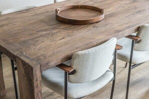 A wooden dining table with a round tray on top, surrounded by four upholstered chairs with metal legs.