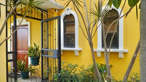 A yellow building with a black gate, potted plants, and a wooden door. - Amazing Ocean View atop Coco Cliffs (Playa del Coco)