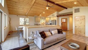 A spacious living area with a large sofa, a dining table, and a kitchen in the background.