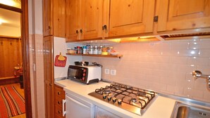 Una cucina con mobili in legno, un fornello a gas, un tostapane e una parete rivestita di piastrelle.