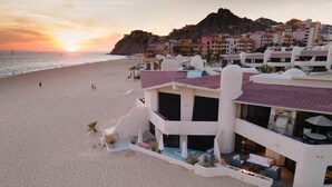 A beachfront hotel with a pool, outdoor seating, and a view of the ocean. - Oceanfront Terrasol Condo with Patio Fireplace (Cabo San Lucas)